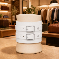 Handgefertigtes weißes Echtleder-Armband mit zwei Lederriemen und silberfarbenen Rollschnallen – stilvoll im Modegeschäft präsentiert.